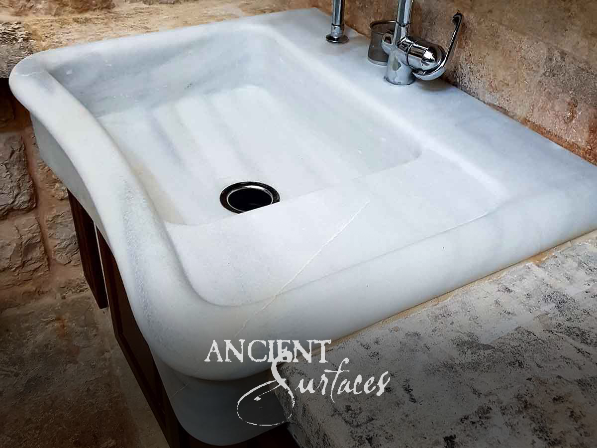 Rectangular white marble washstand sink with sloped apron and single faucet hole