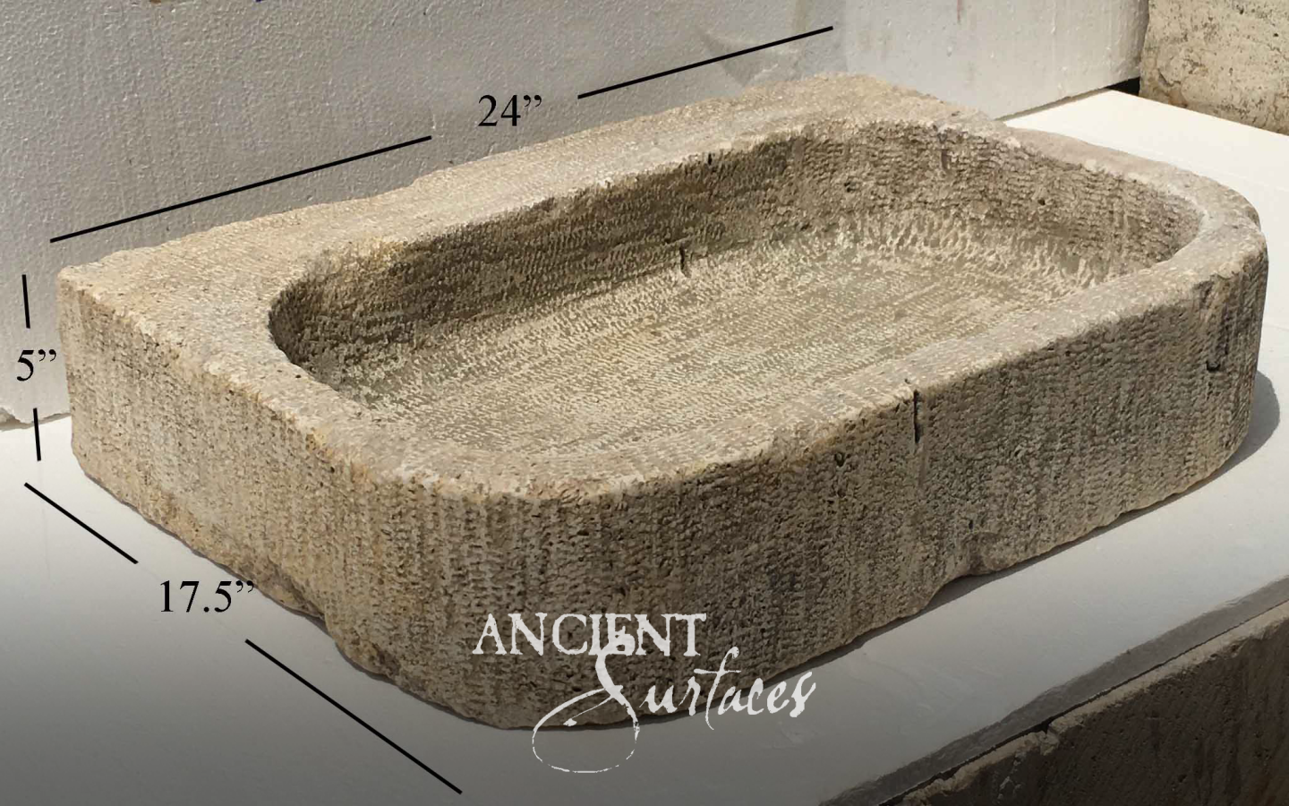 Rectangular beige limestone vessel basin with scooped interior and chiseled walls